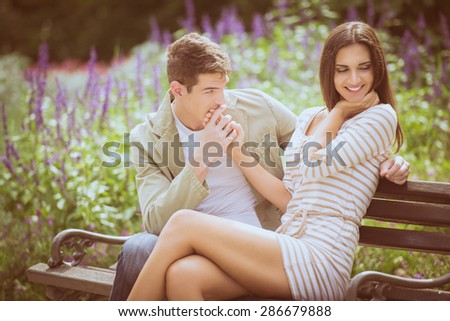 Loving young couple flirting while sitting at a park bench.