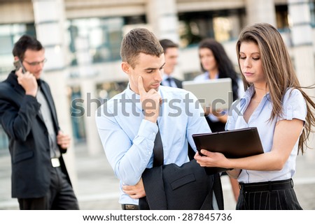 Young businessman talking to his pretty woman business partner in front of office building.