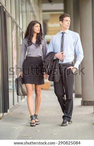 Handsome pair of young businessmen and businesswomen walking outside.