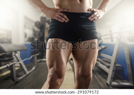 Close up of strong muscular men`s legs in the gym.