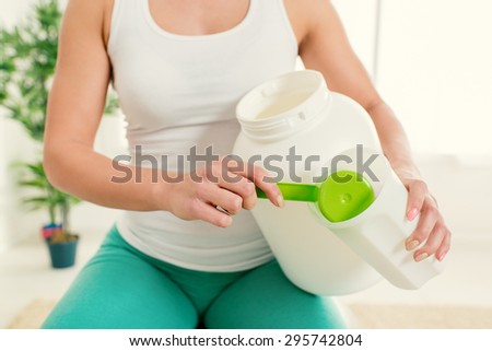 Close-up of a fitness woman pouring Nutritional protein Supplements into shaker.