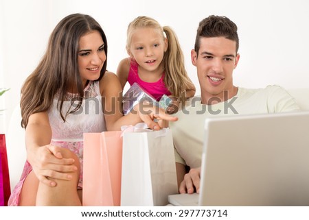 Beautiful happy family sitting at home with shopping bags and looking at laptop.
