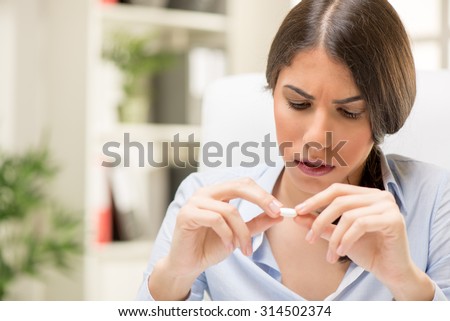 Young beautiful stressed woman takes a pill in the office.