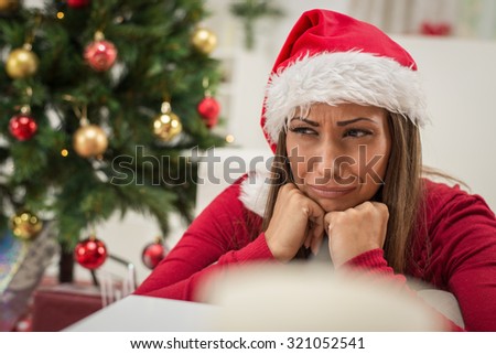Beautiful young woman wearing Santa\'s hat feeling sad at Christmas Time.