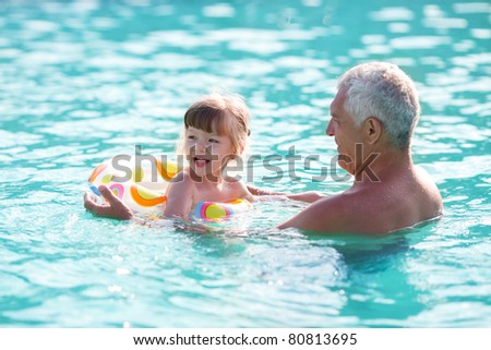 grandfather and granddaughter swimming in the pool