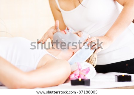 Young beautiful woman receiving cosmetic facial mask in spa beauty salon