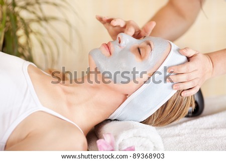Young beautiful woman receiving cosmetic facial mask in spa beauty salon