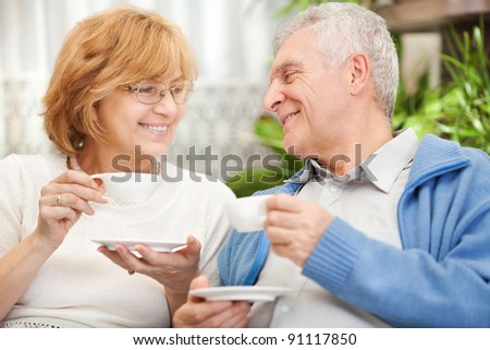 Happy senior couple drinking coffee at home
