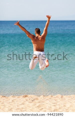 Happy young man in white pants jumping into water