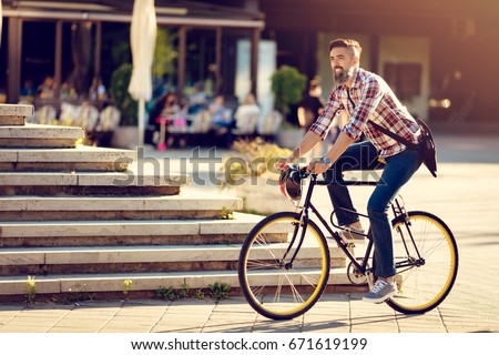 Smiling casual businessman going to work by bicycle.