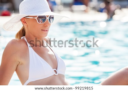 Young beautiful woman enjoying the sun by the pool