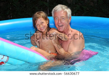Grandfather and granddaughter having fun and floating on a lilo in a swimming pool