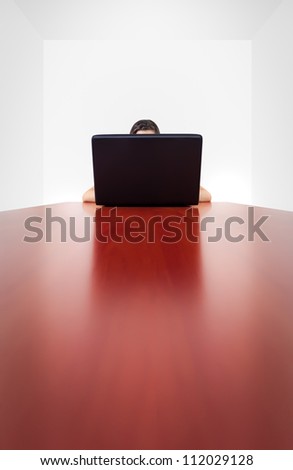 A girl (we can only guess so much) behind a laptop screen, sitting on the far end of a long, shiny table. The image conveys the isolation and anonymity from electronic devices and the Internet.