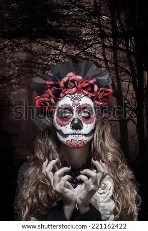 A woman in Halloween costume and skull makeup holding flowers