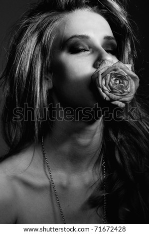 It is a beautiful girl with beautiful eyes and with a rose in to the mouth. for it a breast, beautiful makiyazh and beautiful lips, fashionable beautiful photo, is a bit visible