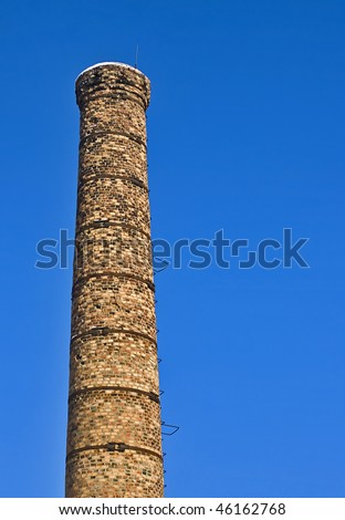Large Decayed Red Brick Boiler House Chimney Against Blue Background