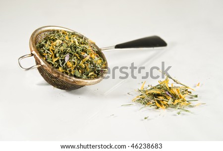 Tea-strainer full of colorful herbs, isolated on white
