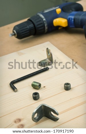 Furniture parts and electric screwdriver on a table in workshop