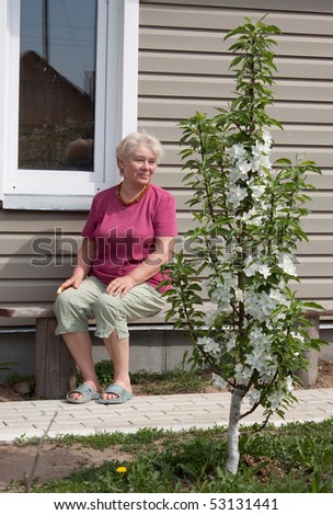 Woman on a summer residence admires blossoming garden
