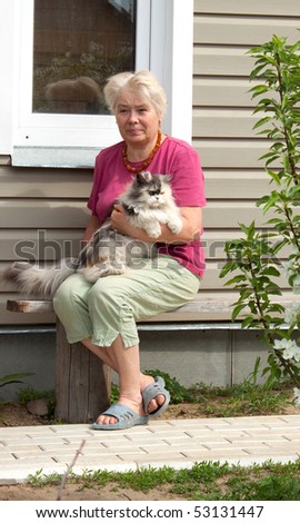Woman sits on summer residence with thoroughbred cat on hands