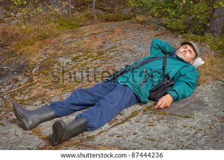 An elderly tourist resting lying on the rock
