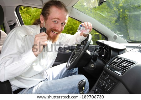 driver smiling sitting in car and showing new car keys and drivers license