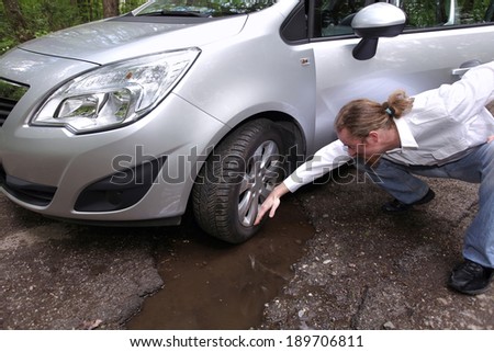 Upset driver man in front of automobile watching damaged car of road full of cracked potholes in pavement
