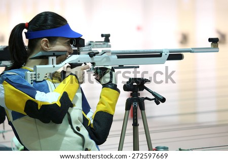 beautiful young woman aiming a pneumatic air rifle
