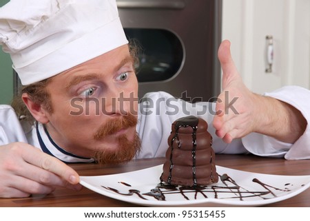 Funny young chef strange looking at piece of cake with chocolate sauce