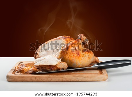 Whole roasted chicken on wooden board with a cut