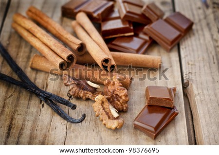 confectionery products. Chocolate, cinnamon, walnuts and vanilla on wooden table