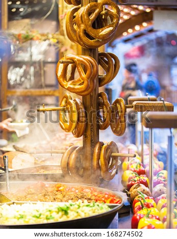A rack of bavarian pretzels and hot steaming meat and vegetables at an outdoor Christmas market in Berlin, Germany