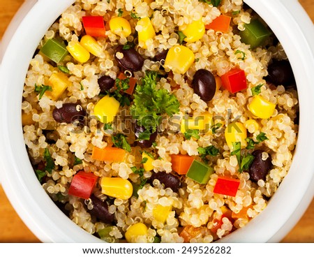 A bowl of healthy quinoa salad with black beans, tomato, corn, parsley and red and green bell peppers