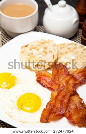 American breakfast including two sunny side up fried eggs, bacon and english muffin