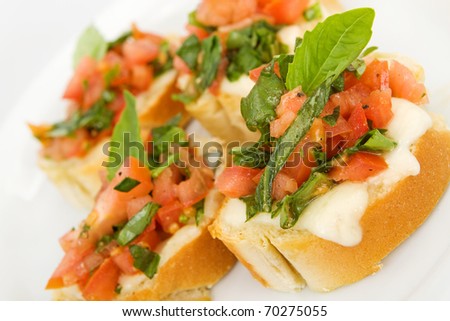 Four pieces of toasted french bread with tomato, basil and mozarella cheese