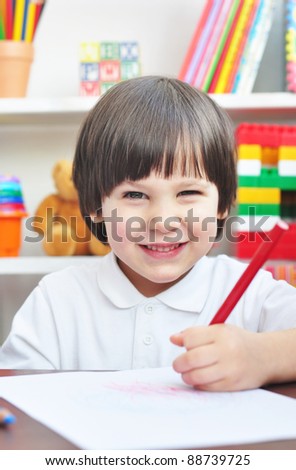 Happy little boy drawing in a preschool
