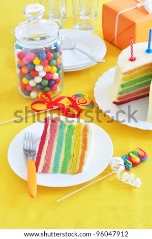 Slice of rainbow cake on the birthday table