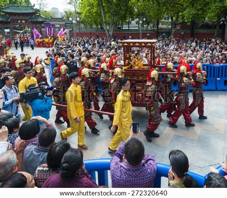 FOSHAN Apr 21:Birthday, Taoist god believers dressed in traditional clothing, carried the gods, patrol, residents along the way to watch and took out his camera phone  April 21, 2015 in Foshan, China