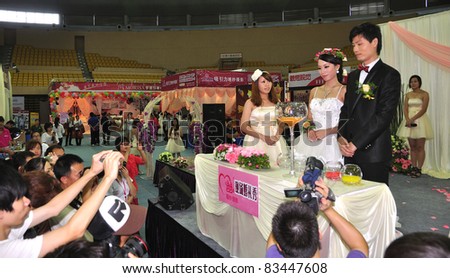 FOSHAN, CHINA–AUG 20: Models pose for photos at the Fall Wedding Expo 2011 at FoShan Stadium on August 20, 2011 in FoShan, China. More than 100 wedding photography, production planning companies took part.