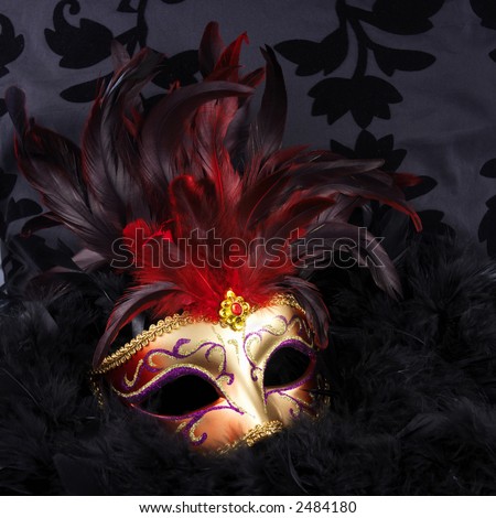 Red and golden mask with black feathers (Venice) on a black velvet background