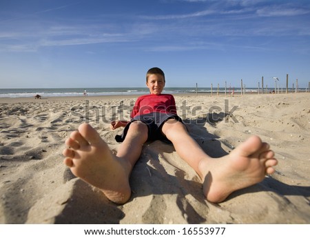 Boy lying down at the beach (wide angel, feet in the front)