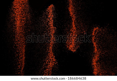 Chili powder, paprika, red spice, falling suspension, on black background