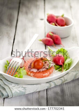 octopus carpaccio over slice grapefruit with radish and lettuce