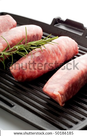 raw sausage with rosemary over grill focus on the second sausage