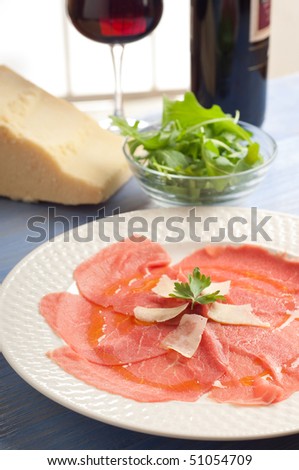 carpaccio with parmesan cheese and bottle of red wine