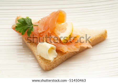 smoked salmon with lemon and butter over toast on dish