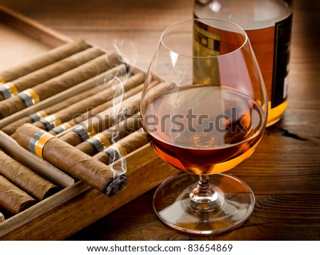 Cuban cigar and bottle of liquor on wood background