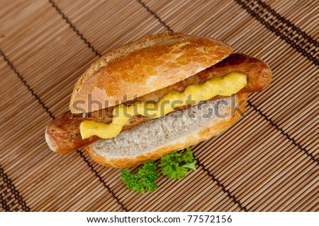 Sausage with mustard in bread roll