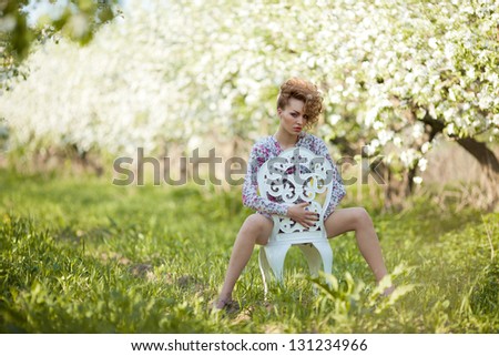beautiful fashion  blonde in the chair in a spring garden