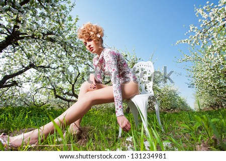 beautiful fashion  blonde in the chair in a spring garden